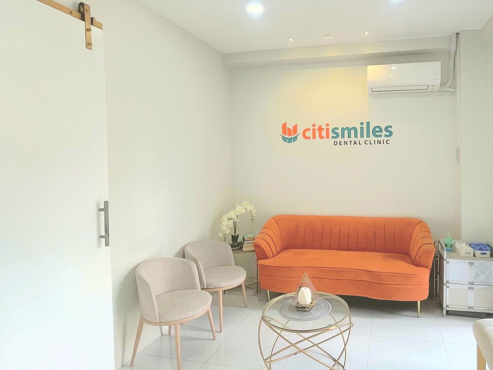 Waiting area with an orange sofa below the Citismiles sign at the clinic in Orion, Bataan